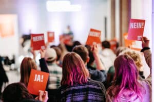 Das Publikum stimmt mit Orangenen Ja/Nein Karten über eine Frage des Podiums ab. Szene aus der Stiftung Forum Recht in Leipzig