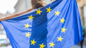 Eine junge Person trägt hinter dem Rücken eine überlebensgroße Europaflagge
