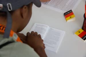 Ein Junger Mann liest das Grundgesetz in englischer Fassung. Aufnahme aus der Perspektive des Schulterblicks.