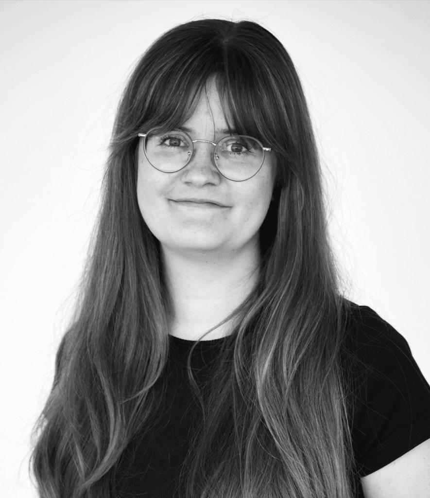 Portrait of a young woman with glasses and shoulder-length hair.