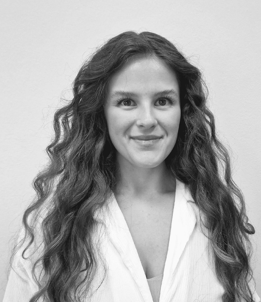 Very young woman with very long curly hair smiles into the camera.