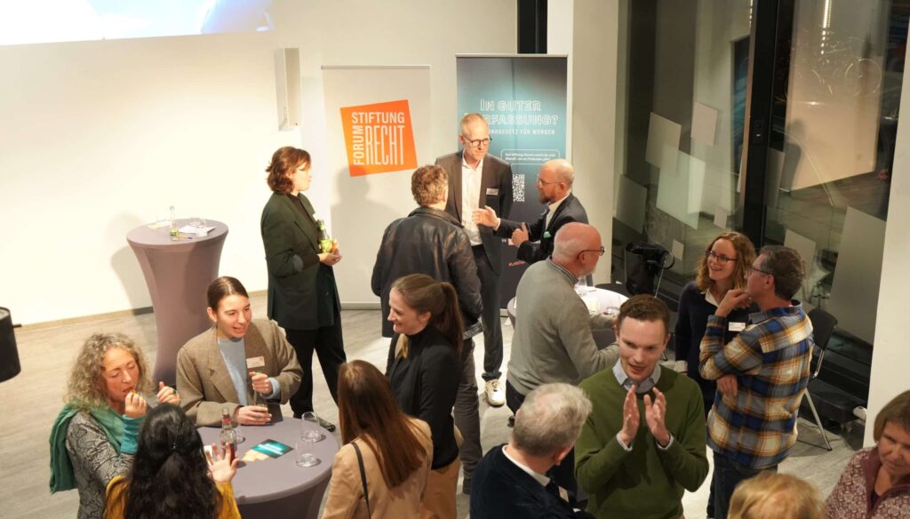 Räume der Stiftung Forum Recht in Karlsruhe von oben fotografiert. Menschen bei einem Empfang, an Stehtischen in Gespräche in Kleingruppen vertieft.