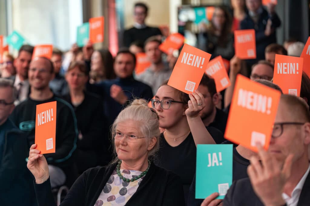 Publikum von vorn mit Ja und Nein-Schildern in den Händen