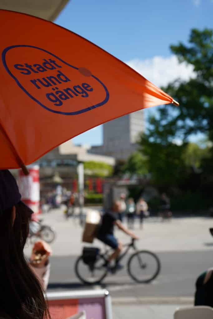 Oranger Schirm mit dem Logo der Stadtrundgänge in Leipzig der Stiftung Forum Recht.