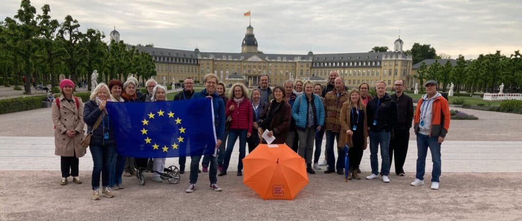 Teilnehmer:innen des Stadtrundgangs in Karlsruhe vor dem Stadtschloss mit Europa-Flagge.
