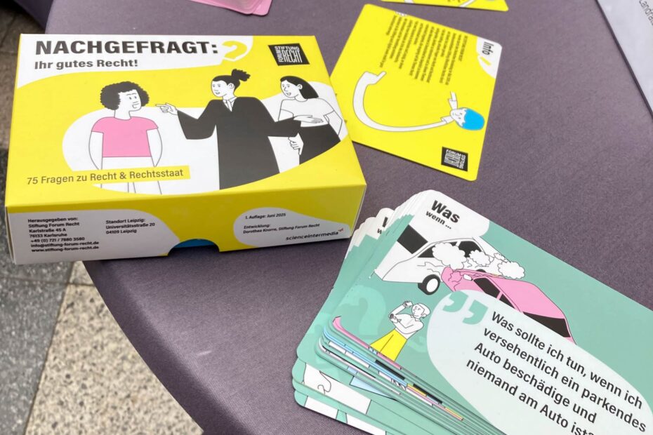 Auf einem Stehtisch liegen mehrere Postkarten mit Fragen und Illustrationen. Daneben eine Pappschachtel mit der Aufschrift "Nachgefragt: Ihr gutes Recht!"