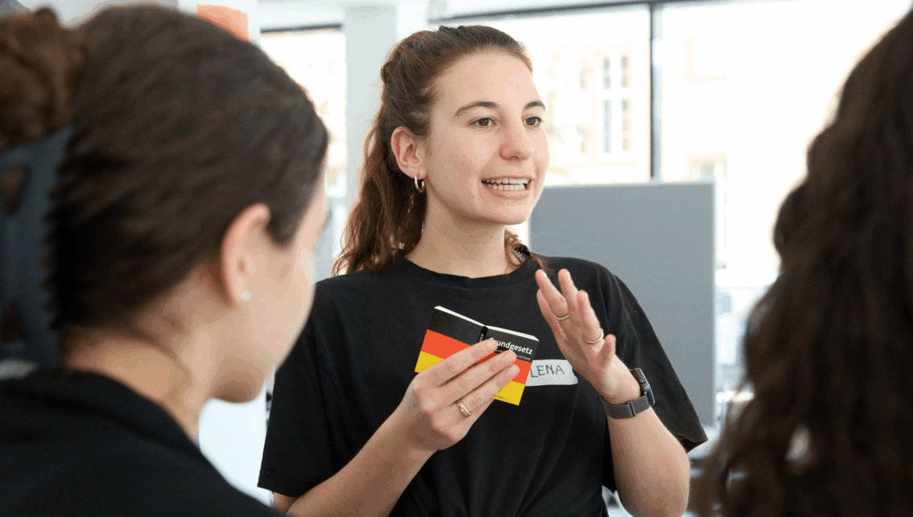 Junge Frau mit Grundgesetz in der Hand argumentier gestenreich.