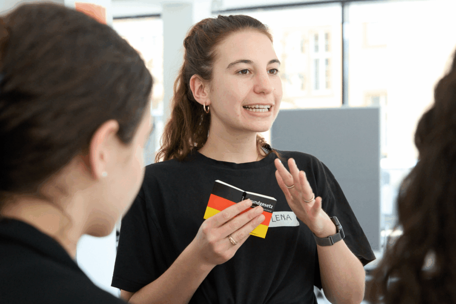 Junge Frau mit Grundgesetz in der Hand argumentier gestenreich.
