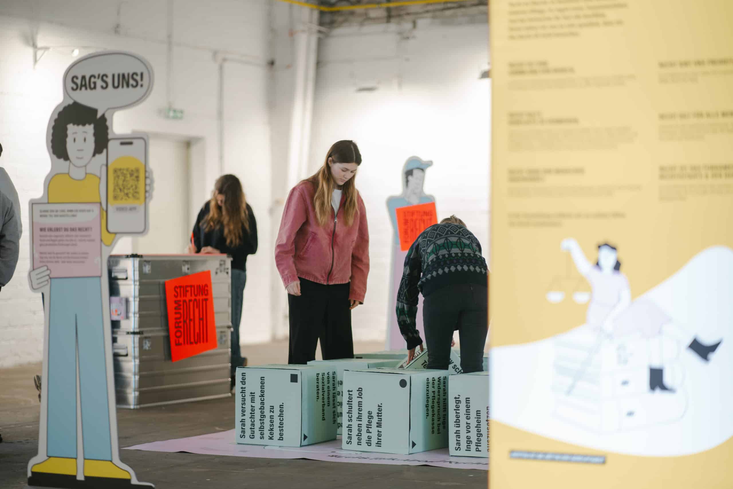 Würfelelemente der Indoor-Ausstellung "Recht - Spielregeln des Alltags" mit Menschen, die sie bespielen.
