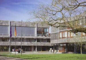 Außenansicht des Bundesverfassungsgerichts in Karlsruhe mit einer Gruppe Besuchender vor dem Eingang.