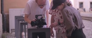 Three teenagers are looking at a movie camera