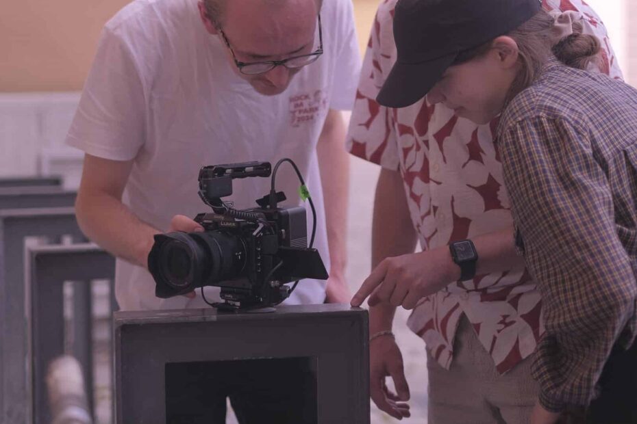 Three teenagers are looking at a movie camera