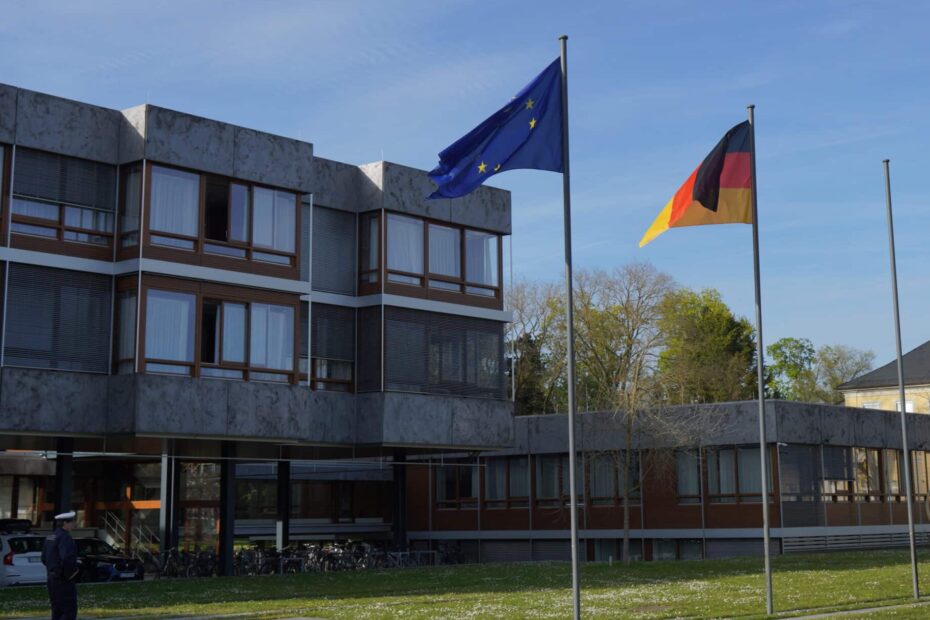 Außenansicht des Bundesverfassungsgerichts in Karlsruhe mit einer Deutschlandflagge und der Fahne der EU im Vordergrund