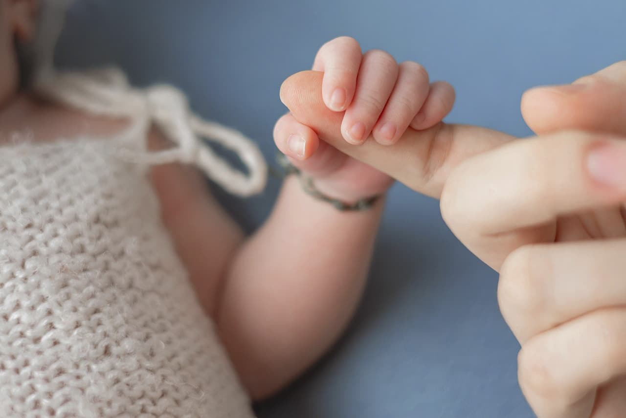 Baby's hand wraps around a finger