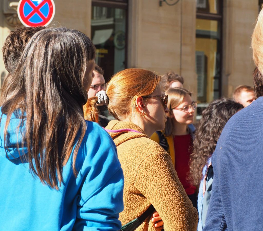 Eine Gruppe von Teilnehmer:innen des Stadtrundgangs von der Seite abgebildet. Die Sonne scheint auf ihre leichte Herbstkleidung